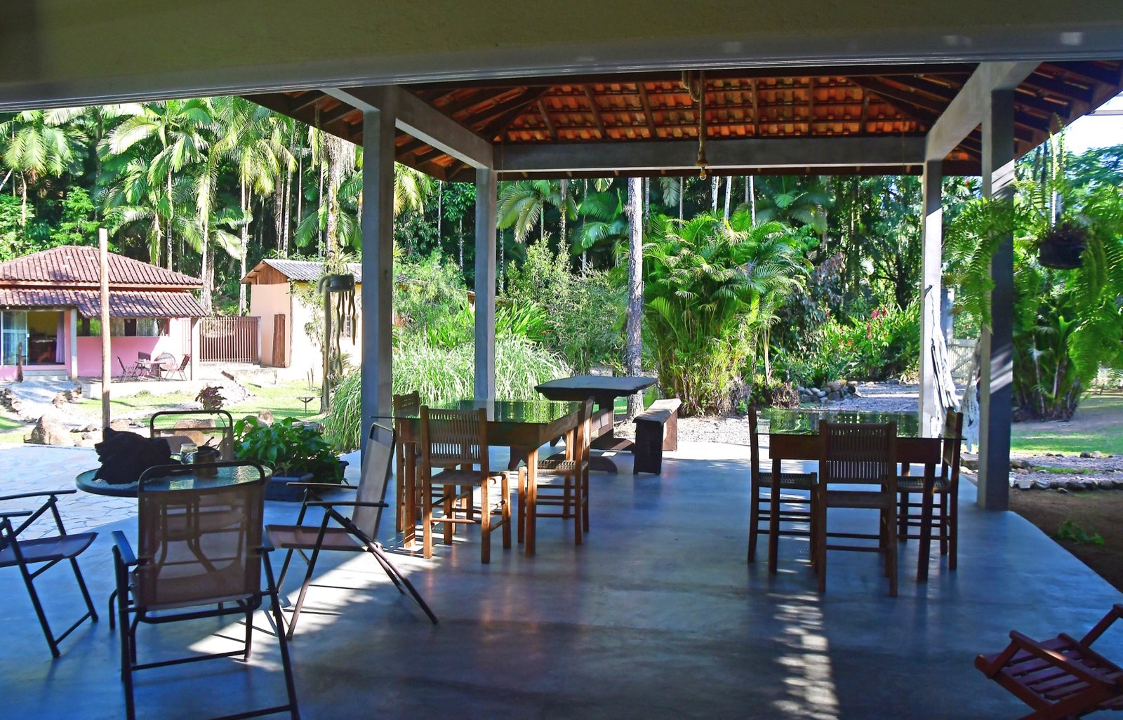 Área coberta com mesas e vista para a casa e o jardim